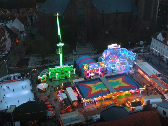 Blick aus der Luft auf den Neuen Markt in Stralsund mit Fahrgeschäften und Eisbahn