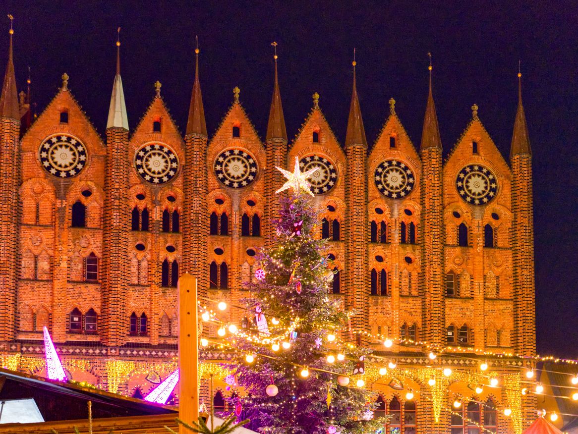 Besucher genießen den traditionellen Weihnachtsmarkt auf dem Alten Markt Stralsund vor der historischen Kulisse des Stralsunder Rathauses.